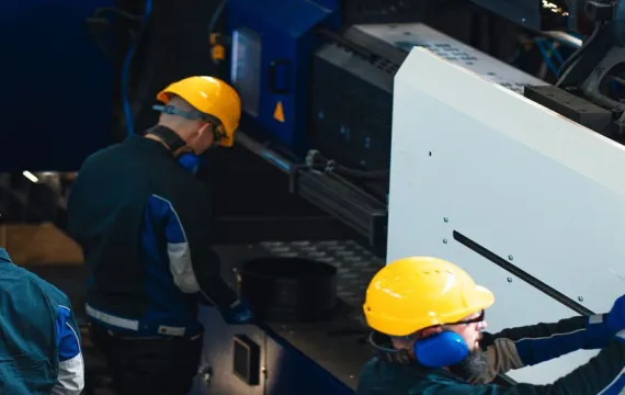 A group of workers in safety gear is seen operating and overseeing heavy machinery