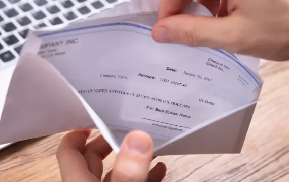 Person's hand removing paycheck from the envelope