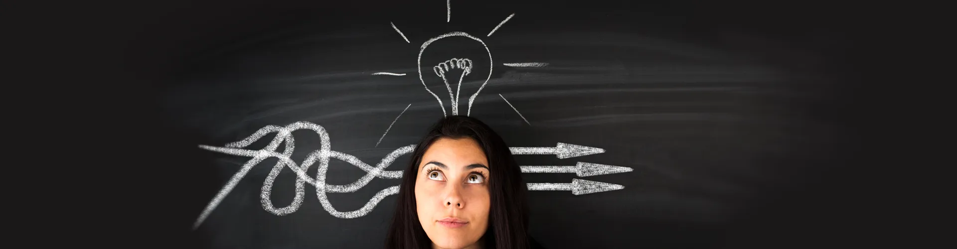Woman standing in front of a chalkboard with a lightbulb above her head