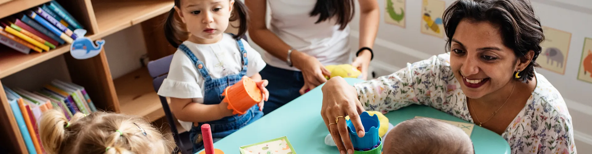 Preschool teacher sitting around table with children