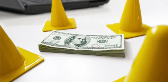 Safety cones surrounding a stack of money