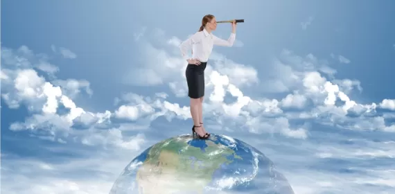 Businesswoman searching through telescope on top of the world